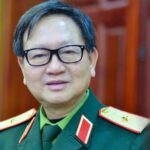Portrait of a middle aged man in a green military uniform with glasses standing indoors